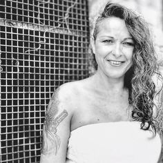 black and white photograph of a woman with tattoos on her arm, smiling at the camera