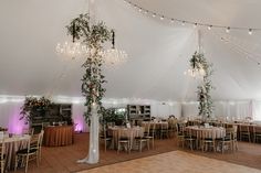 the inside of a tent with tables and chairs set up for a wedding reception at night