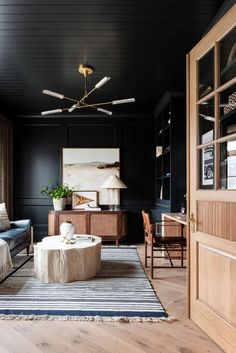 a living room with black walls and wooden furniture in the center, along with a striped rug on the floor