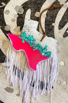 a piece of fabric with fringes and flowers on it sitting on top of a rug