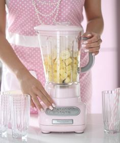 a woman using a blender filled with bananas