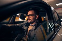 a man wearing glasses sitting in a car