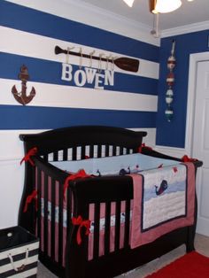 a baby's room decorated in blue and white stripes with an anchor on the wall