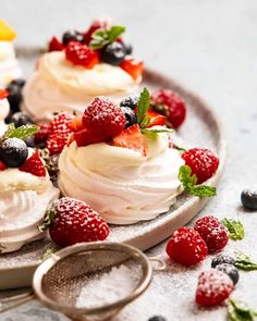 small desserts with berries and whipped cream on a plate next to a measuring spoon