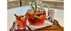 a pitcher and two glasses filled with liquid on a tray next to each other,