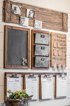 a wall with several calendars hanging on it and flowers in a basket next to them