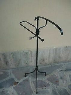 a black metal coat rack with two coats on it's sides and an umbrella stand