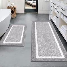 two bathroom rugs on the floor in front of a bathtub and sink area