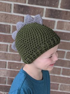 a young boy wearing a green knitted hat with flowers on the front and side