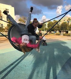 two people are playing on swings in the park