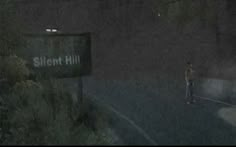 a man standing on the side of a road in the rain next to a street sign