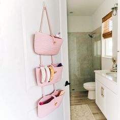 a pink purse hanging on the wall next to a white toilet and sink in a bathroom