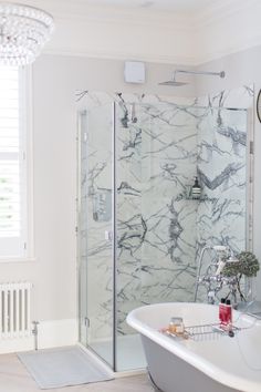 a white bath tub sitting next to a shower in a bathroom under a chandelier