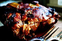 a piece of meat sitting on top of a wooden table next to a knife and fork