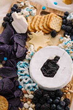 an assortment of snacks including crackers, blueberries and cheese on a cutting board