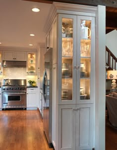 a kitchen with white cabinets and stainless steel appliances, along with hardwood floors is shown