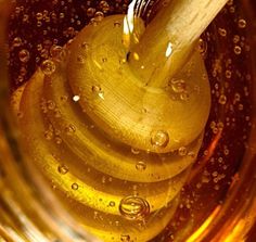 a wooden spatula in a glass filled with oil and water droplets on the surface