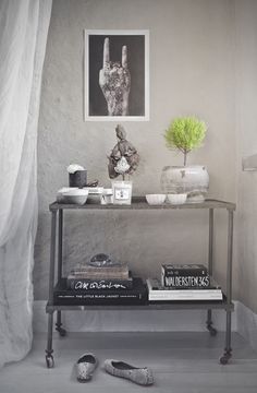 a shelf with books, plants and pictures on it