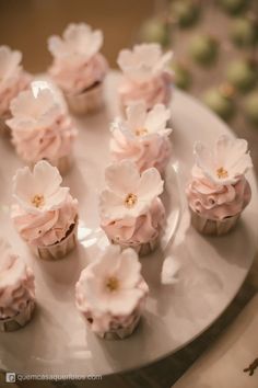 cupcakes with pink frosting and flowers on a plate