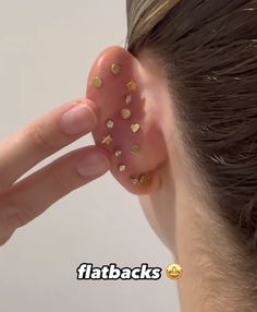 a woman is holding her ear with gold studs on the top and bottom of it