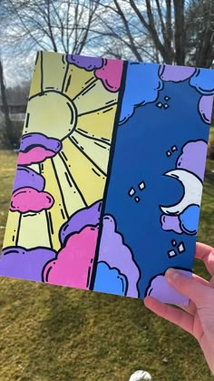 someone holding up two different colored cards in their hand, one with an image of the sun and clouds on it