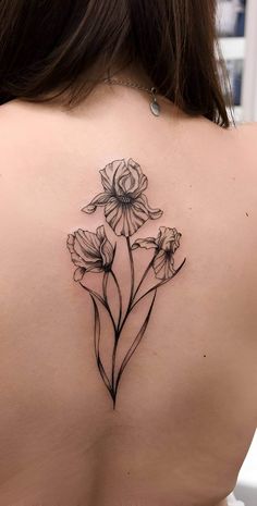 the back of a woman's shoulder with flowers tattoo on her left upper arm