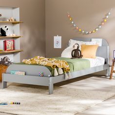 a child's bedroom with a bed, bookshelf and toys on the floor