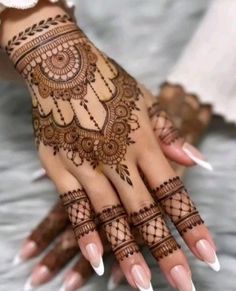 a woman's hand with henna tattoos on it