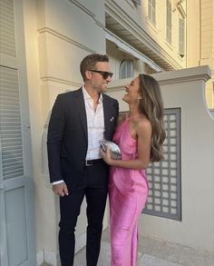 a man in a suit and woman in a pink dress standing next to each other