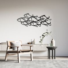 a chair and table in a room with a large metal fish wall art on the wall