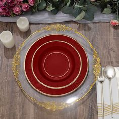 a red plate with gold trim on it next to silverware and flowers in the background