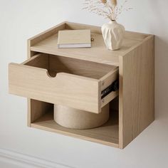 an open drawer on the wall with a vase and book