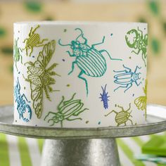 a cake with bugs on it sitting on top of a silver plate next to green and white napkins