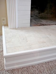 an empty room with a fireplace and white trim on the wall, carpeted floor