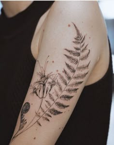 a woman with a tattoo on her arm has a fern and flower design on it