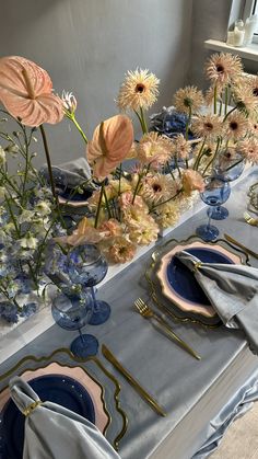 the table is set with blue and white plates, silver napkins, and flowers