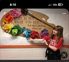 a girl is standing in front of a bulletin board with clothes on it that says art is not what you see