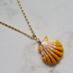 "Hawaiian Sunrise Shell Necklace~ This necklace has a beautiful orange and pink wire wrapped Hawaiian sunrise shell on gold fill chain. Sunrise shells are only found in Hawaii, a true gem to the islands and collectors. Shell approx. 1\" Chain is adjustable 18.5\"-19.5\" Model wearing similar necklace Checkout our sunrise shell jewelry~ https://www.etsy.com/shop/HanaMauiCreations?ref=seller-platform-mcnav&search_query=sunrise+shell+jewelry SHOP~ http://www.etsy.com/shop/HanaMauiCreations?ref=si_s Pink Shell-shaped Necklace For Beach, Handmade Yellow Gold Necklaces For The Beach, Wire Wrapped Shell Necklace For Beach, Wire Wrapped Shell Necklaces In Shell Shape, Beach Wire Wrapped Shell, Wire Wrapped Shell Necklaces, Gold Wire Wrapped Shell Necklace, Handmade Gold Shell Strand, Handmade Gold Strand Shell