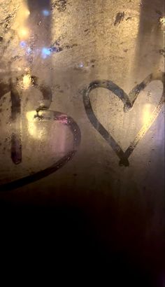 two hearts are drawn on the glass with light from street lamps in the back ground