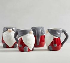 three ceramic santa claus mugs sitting next to each other