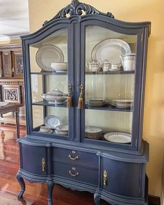 a blue china cabinet with plates and dishes on it