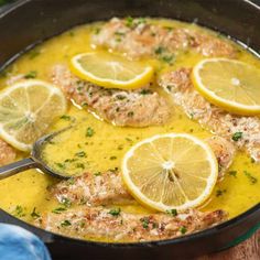 a pan filled with fish and lemons on top of a wooden table