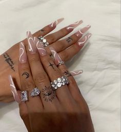 a woman's hands with pink and white nail polish on them, holding three different rings