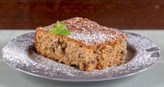 a piece of cake sitting on top of a plate covered in powdered sugar and sprinkled with a green leaf