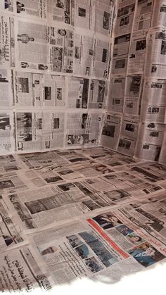 a toilet covered in newspapers sitting on top of a bathroom floor next to a wall