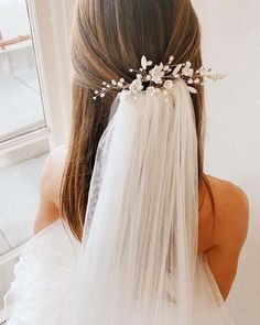 a woman wearing a veil and flowers in her hair is looking out the window at something outside