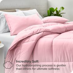 a bed with pink sheets and pillows on top of it, next to a plant