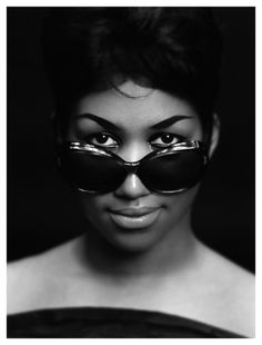 a woman with sunglasses on her face is posing for the camera in front of a black background