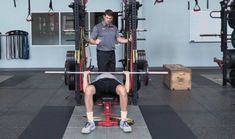 a man is doing squats on a bench in a gym with barbells