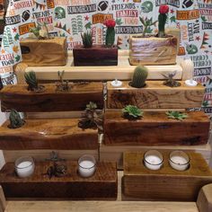 several wooden boxes with candles and succulents on them in front of a wall